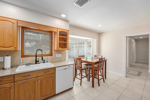 kitchen featuring visible vents, decorative backsplash, white dishwasher, light countertops, and a sink