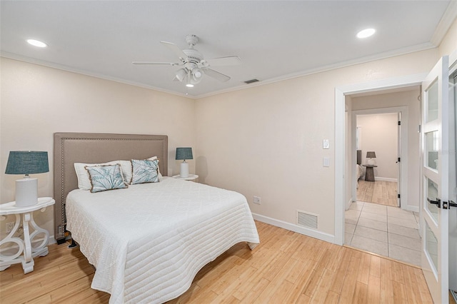 bedroom with light wood-style flooring, visible vents, baseboards, and ornamental molding