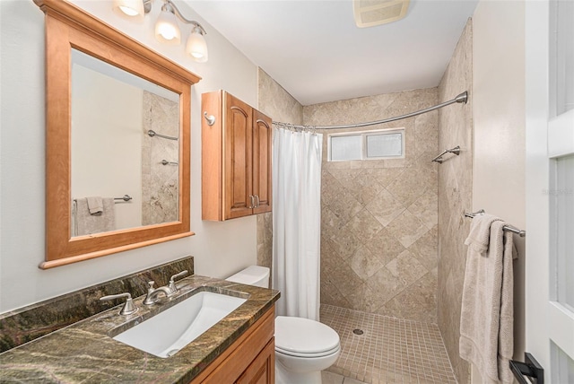 bathroom featuring visible vents, vanity, a tile shower, and toilet