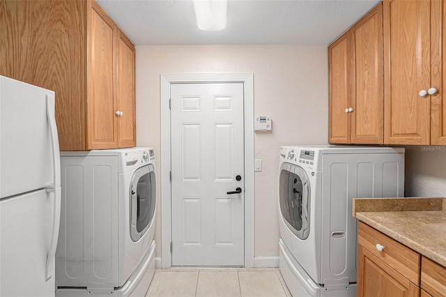 washroom featuring light tile patterned floors, independent washer and dryer, cabinet space, and baseboards