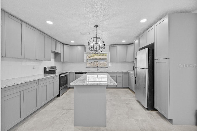 kitchen featuring stainless steel appliances, decorative backsplash, gray cabinetry, a sink, and a kitchen island