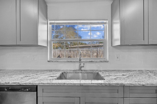 kitchen with dishwasher, backsplash, a sink, and gray cabinetry