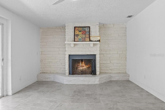 unfurnished living room with visible vents, a fireplace, a textured ceiling, and baseboards