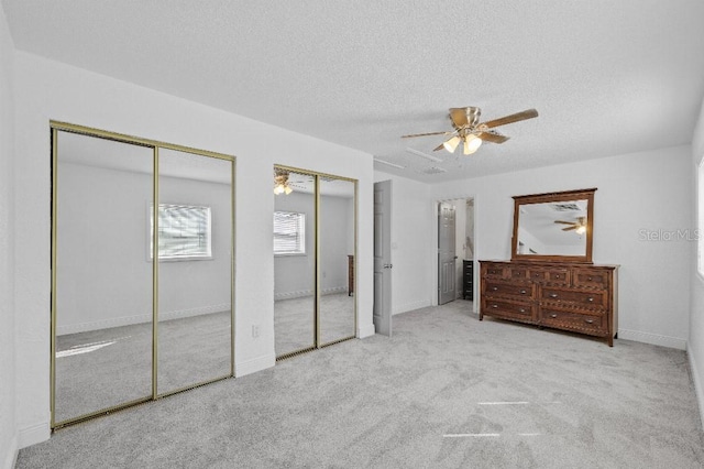 carpeted bedroom with ceiling fan, a textured ceiling, baseboards, and multiple closets