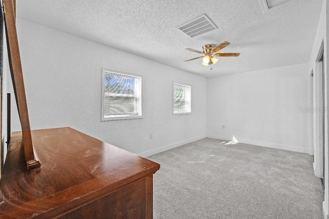 unfurnished bedroom with a textured ceiling, a ceiling fan, visible vents, baseboards, and carpet