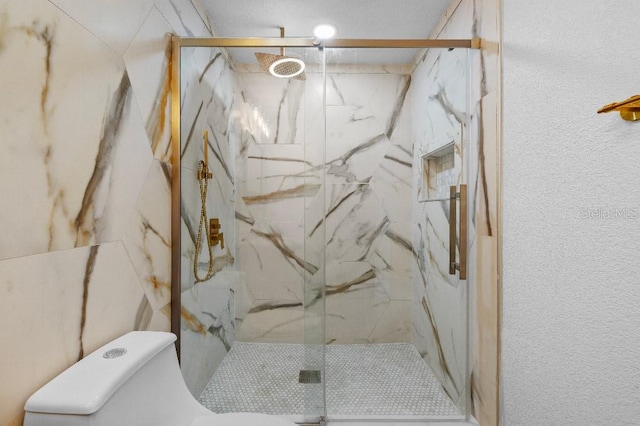 bathroom with a marble finish shower and toilet