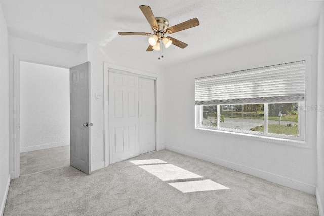 unfurnished bedroom featuring ceiling fan, carpet floors, a closet, and baseboards