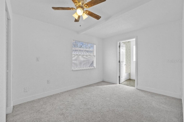 spare room with a ceiling fan, light colored carpet, and baseboards