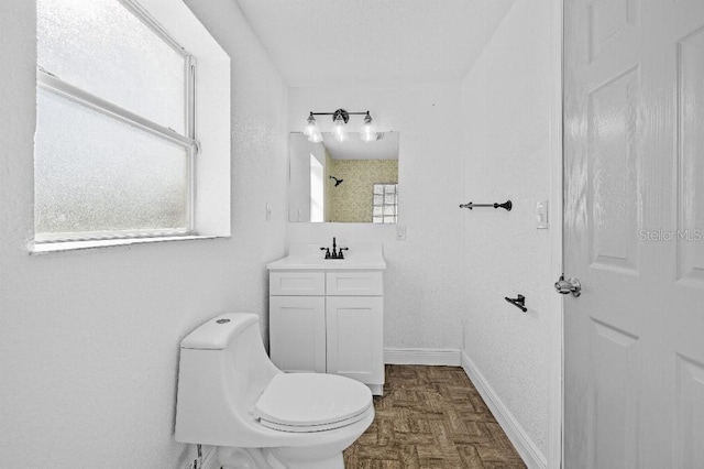 bathroom featuring baseboards, vanity, and toilet