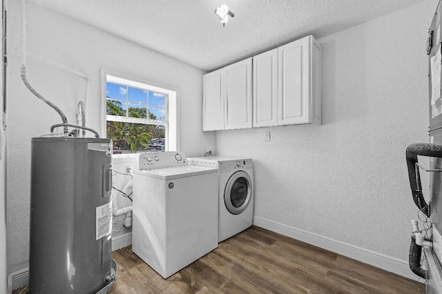 washroom featuring dark wood finished floors, washing machine and clothes dryer, cabinet space, electric water heater, and baseboards