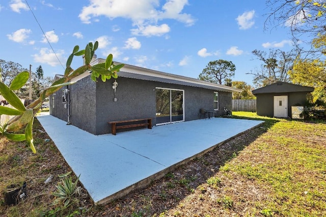 rear view of house with a patio area, fence, stucco siding, and an outdoor structure