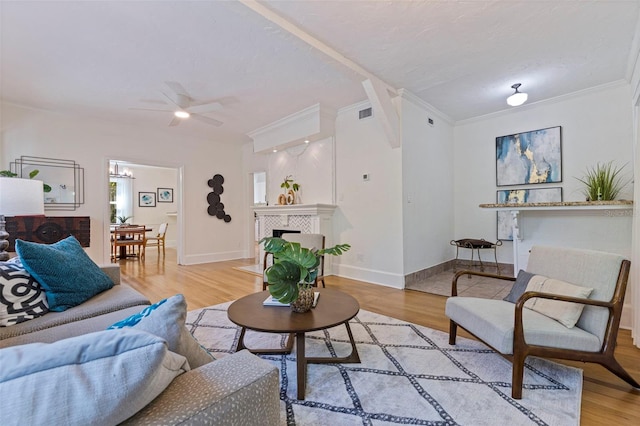 living area with crown molding, baseboards, a tile fireplace, and light wood-style floors