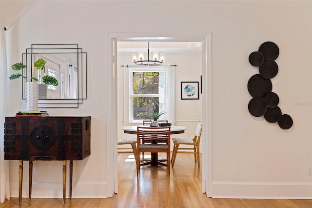 dining area featuring a notable chandelier, light wood-type flooring, and baseboards