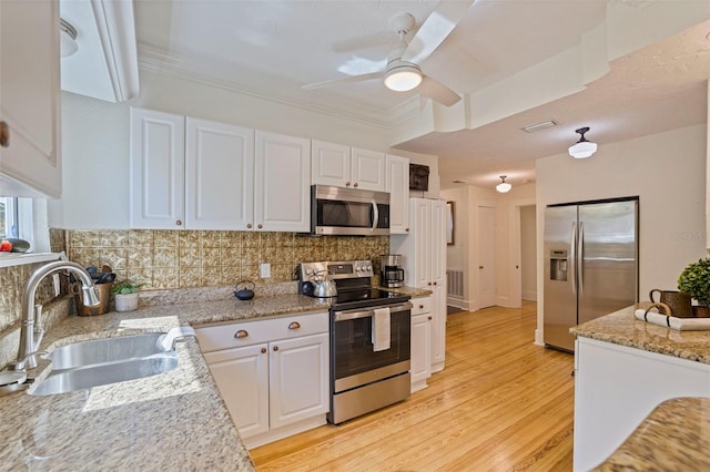 kitchen featuring tasteful backsplash, light wood-style flooring, stainless steel appliances, white cabinetry, and a sink