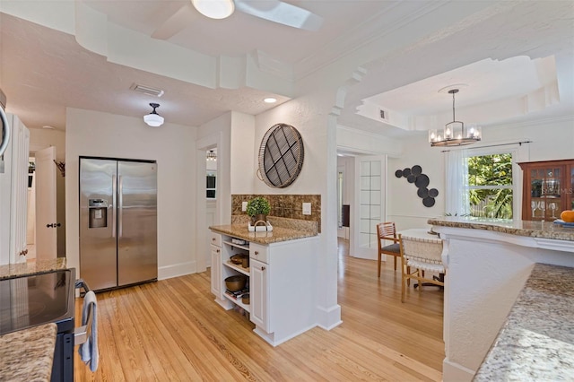 kitchen with white cabinets, a raised ceiling, stainless steel fridge with ice dispenser, light wood-style flooring, and open shelves