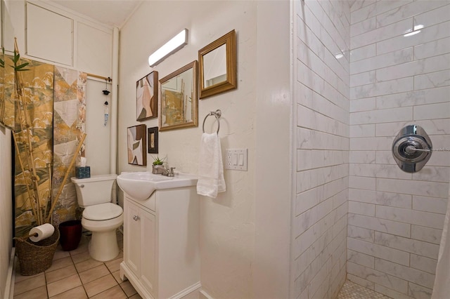 full bath featuring toilet, tile patterned flooring, tiled shower, and vanity