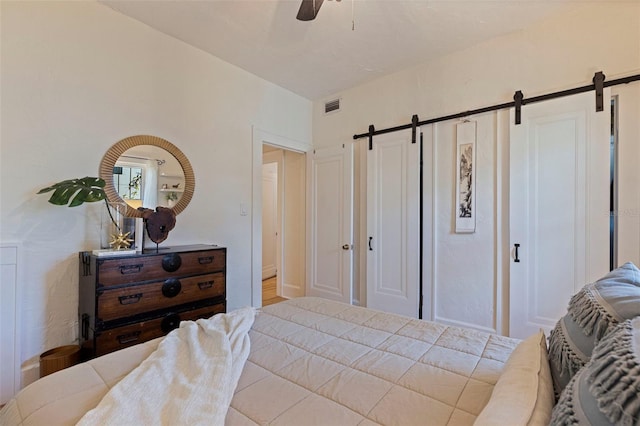 bedroom with a ceiling fan, visible vents, and a barn door