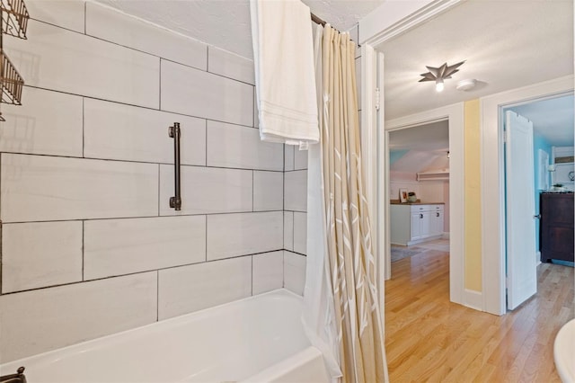 full bathroom featuring shower / tub combo, baseboards, and wood finished floors