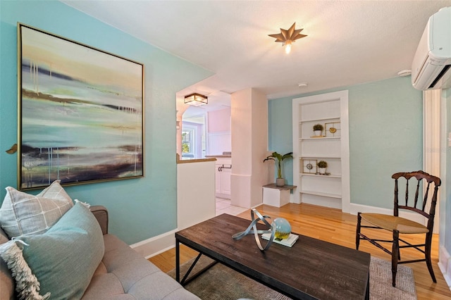 living room featuring light wood-type flooring, baseboards, and a wall mounted AC