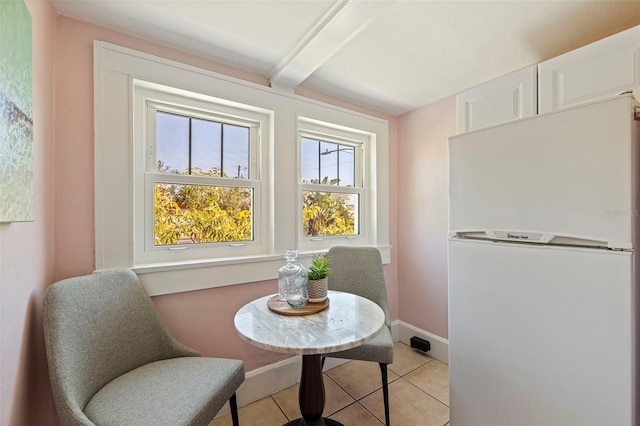 dining room featuring light tile patterned flooring, beam ceiling, and baseboards