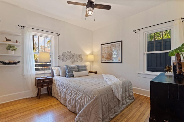 bedroom with a ceiling fan, light wood-style flooring, and baseboards