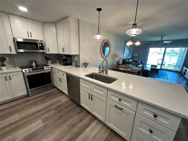 kitchen featuring dark wood-style floors, decorative backsplash, appliances with stainless steel finishes, white cabinetry, and a sink