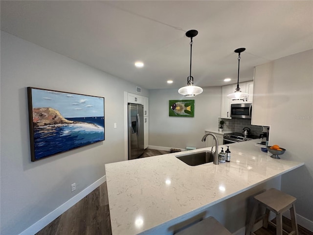 kitchen with stainless steel appliances, backsplash, white cabinets, a sink, and a peninsula