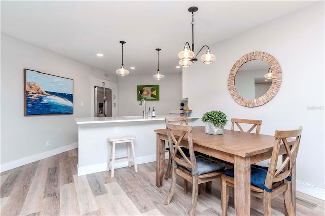 dining room with recessed lighting, light wood-style flooring, and baseboards