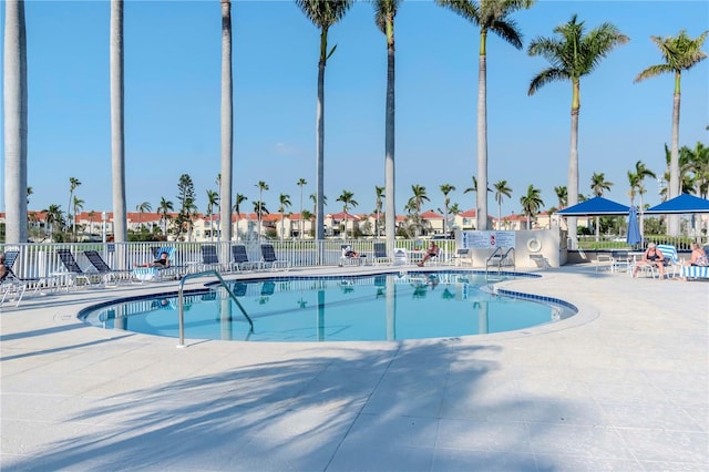 community pool with a patio and fence