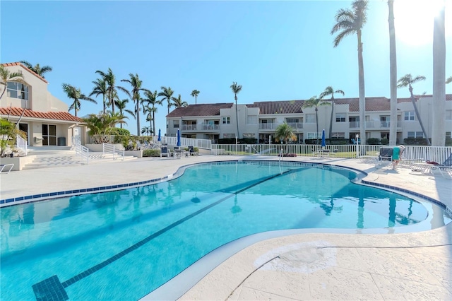 pool with a patio area, a residential view, and fence