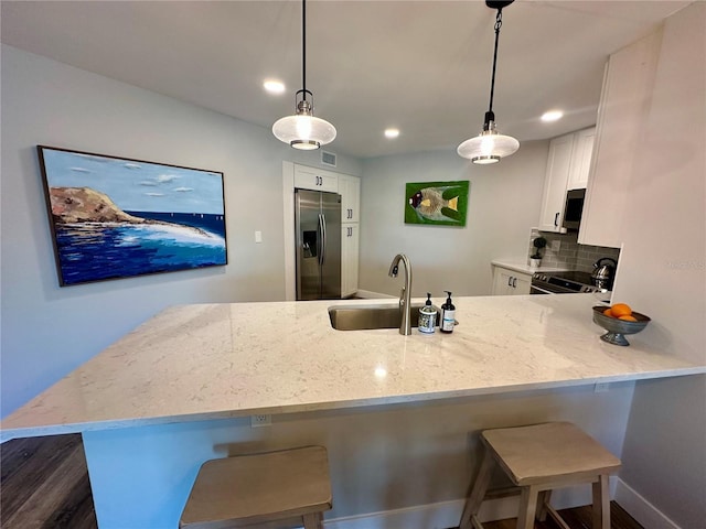 kitchen featuring stainless steel appliances, white cabinets, a sink, and light stone counters