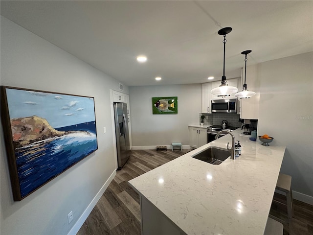 kitchen with stainless steel appliances, a peninsula, a sink, and white cabinetry