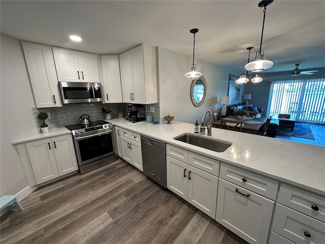 kitchen featuring stainless steel appliances, a sink, backsplash, and dark wood-style floors