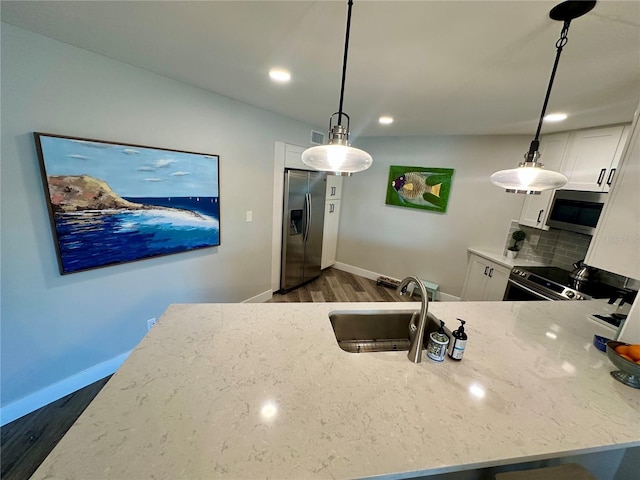 kitchen featuring dark wood-style flooring, stainless steel appliances, white cabinets, a sink, and light stone countertops