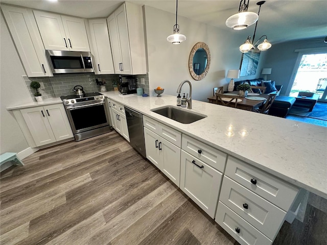 kitchen with a sink, white cabinetry, appliances with stainless steel finishes, decorative backsplash, and dark wood finished floors