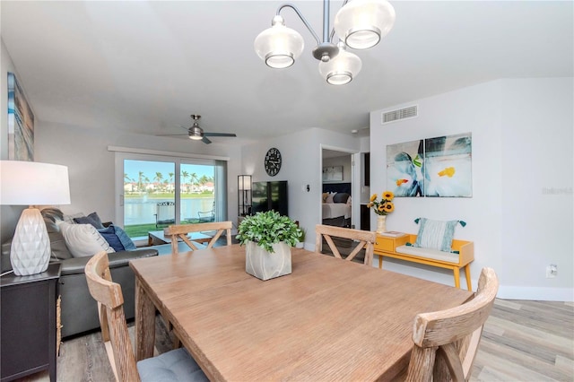 dining space featuring light wood finished floors, baseboards, visible vents, and ceiling fan with notable chandelier