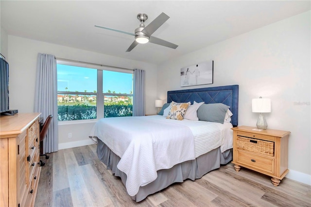 bedroom with light wood finished floors, a ceiling fan, and baseboards