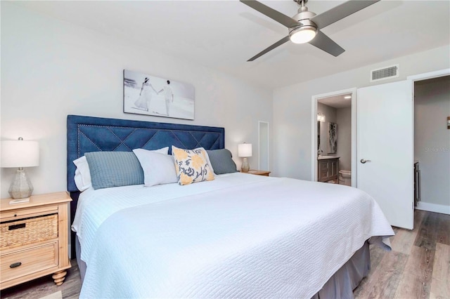 bedroom with connected bathroom, wood finished floors, a ceiling fan, baseboards, and visible vents