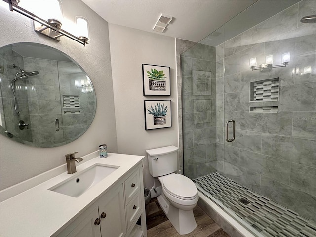 bathroom featuring toilet, a stall shower, wood finished floors, and visible vents