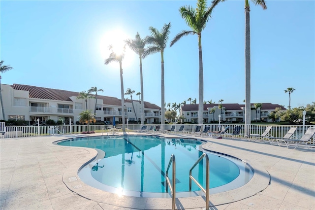 community pool with a patio area, a residential view, and fence