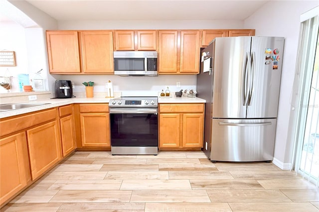 kitchen with appliances with stainless steel finishes, wood tiled floor, and light countertops