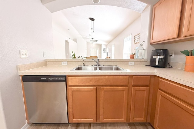 kitchen featuring stainless steel dishwasher, a peninsula, light countertops, and a sink