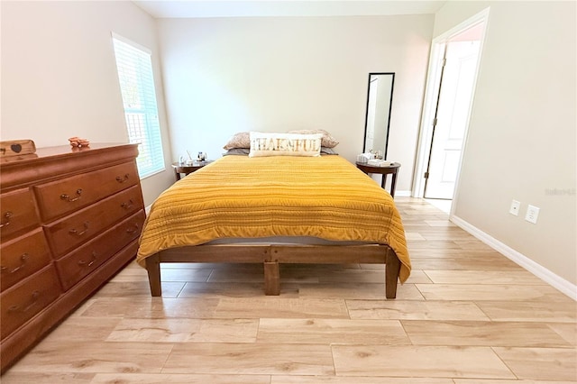 bedroom featuring baseboards and light wood finished floors