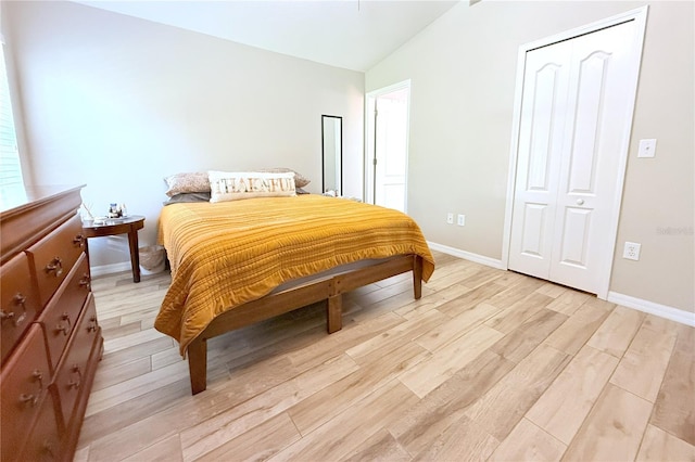 bedroom featuring vaulted ceiling, light wood-style flooring, and baseboards