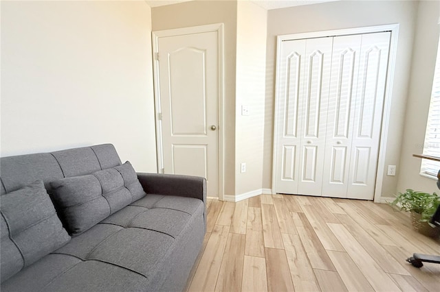 living area featuring baseboards and light wood finished floors