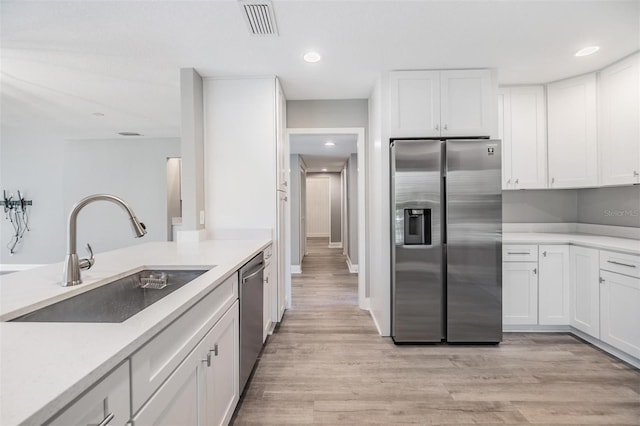 kitchen featuring visible vents, a sink, light wood-style floors, appliances with stainless steel finishes, and white cabinetry