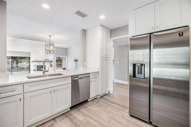 kitchen featuring visible vents, a sink, stainless steel appliances, white cabinets, and light countertops