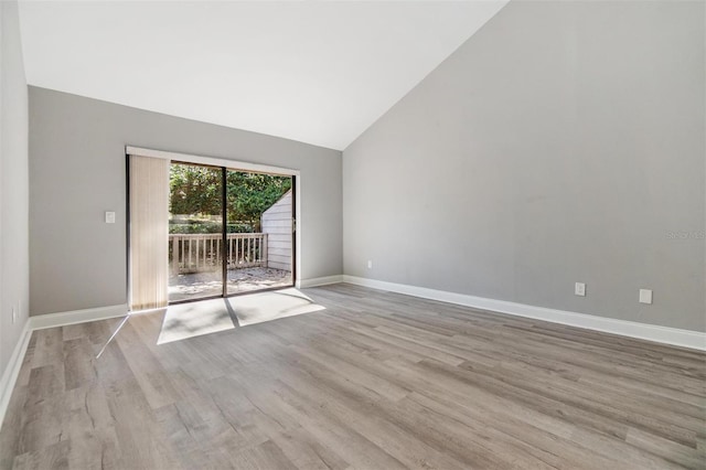 unfurnished room featuring wood finished floors, baseboards, and high vaulted ceiling