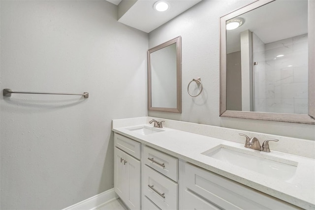 bathroom featuring a sink, baseboards, walk in shower, and double vanity