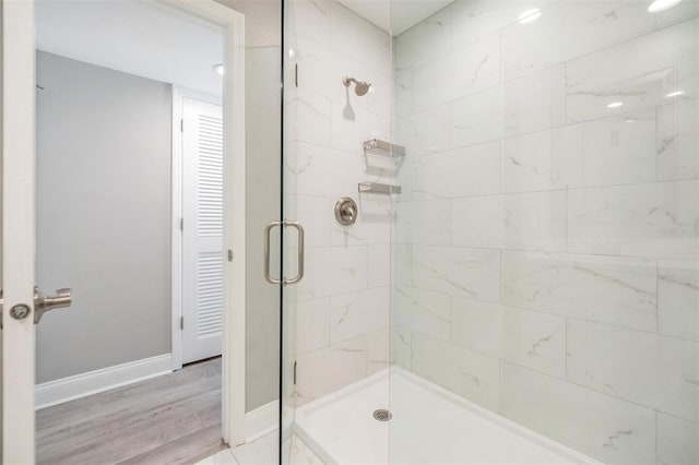 bathroom featuring wood finished floors, baseboards, and a stall shower